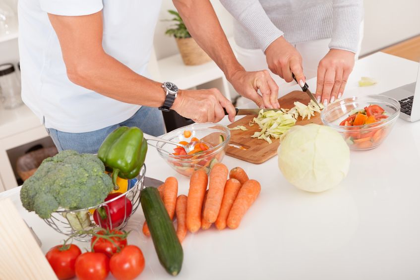 middle-aged couple preparing a meal chopping vegetables in their kitchen food safety