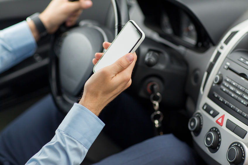 man holding a cell phone and driving