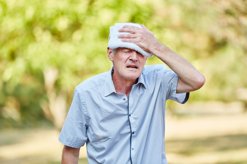 senior man with bad circulation cools his head with wet cloth