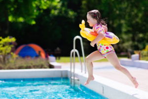 60322447 - happy little girl with inflatable toy ring jumping into outdoor swimming pool in a tropical resort during family summer vacation. kids learning to swim. water fun for children.