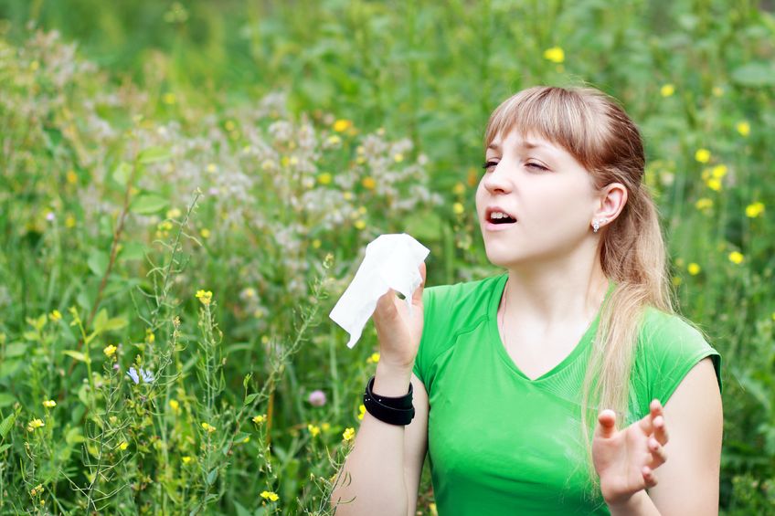 21878836 - young woman sneezing in a flowers meadow. concept: seasonal allergy