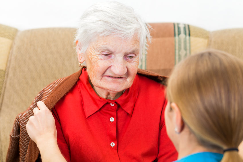 Young carer wrap the elderly woman with warm sweater