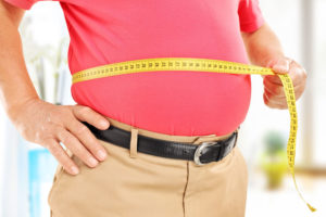 36357182 - close-up on a man measuring his belly at home
