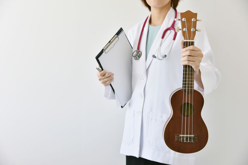 Doctor hand holding ukulele (musical instrument), Music therapy concept.