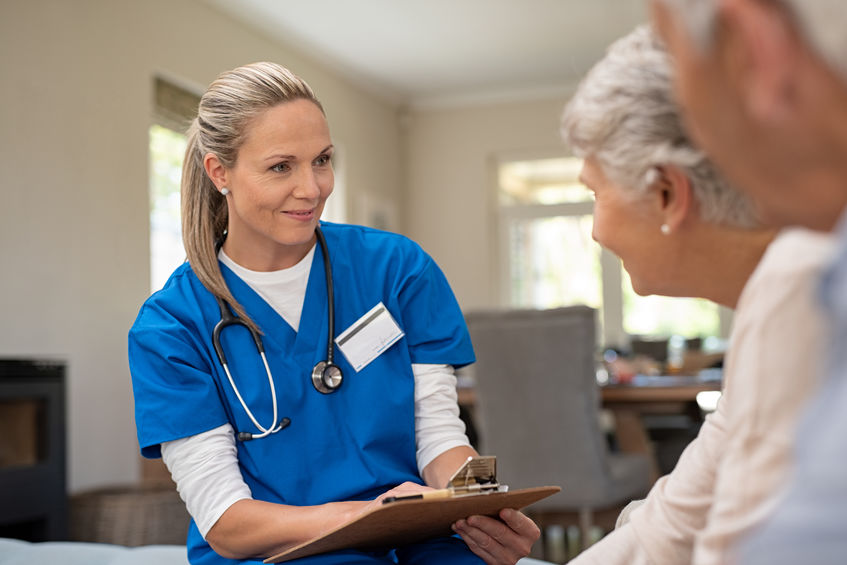 Happy nurse talking to senior patients in private clinic. Senior couple consulting health and medical report with doctor at home. Old man and elderly woman visiting the nurse with clipboard and health issues.