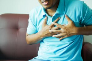a man holding his chest as he experiences chest pain