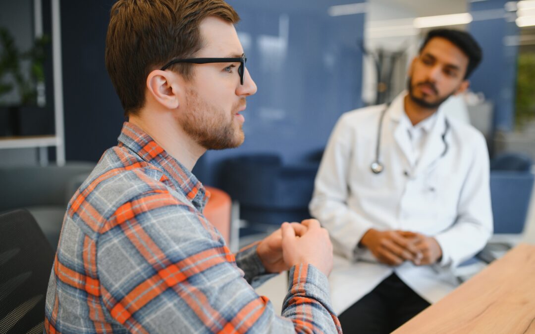 medicine, healthcare and people concept - indian doctor giving prescription to male patient at clinic.