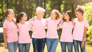 Breast Cancer Volunteers. Women In Pink Ribbon Awareness T-Shirts Embracing Standing Outdoor. Panorama