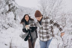 A young happy and loving couple walking in a snowy forest in the mountains.