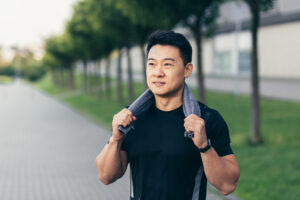 asian man after fitness workout and jogging happy man smiling shows thumb up and looks at camera.