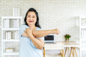 Morning work-out, Senior asian woman doing fitness exercises from home, Fitness woman doing stretch exercise stretching her arms, Elderly woman living an active lifestyle.