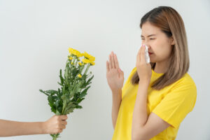 Pollen Allergies, asian young woman sneezing in a handkerchief or blowing in a wipe, allergic to wild spring flowers or blossoms during spring. allergic reaction, respiratory system problems