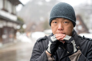 an asian man standing outside depicting someone who might be experiencing seasonal depression.